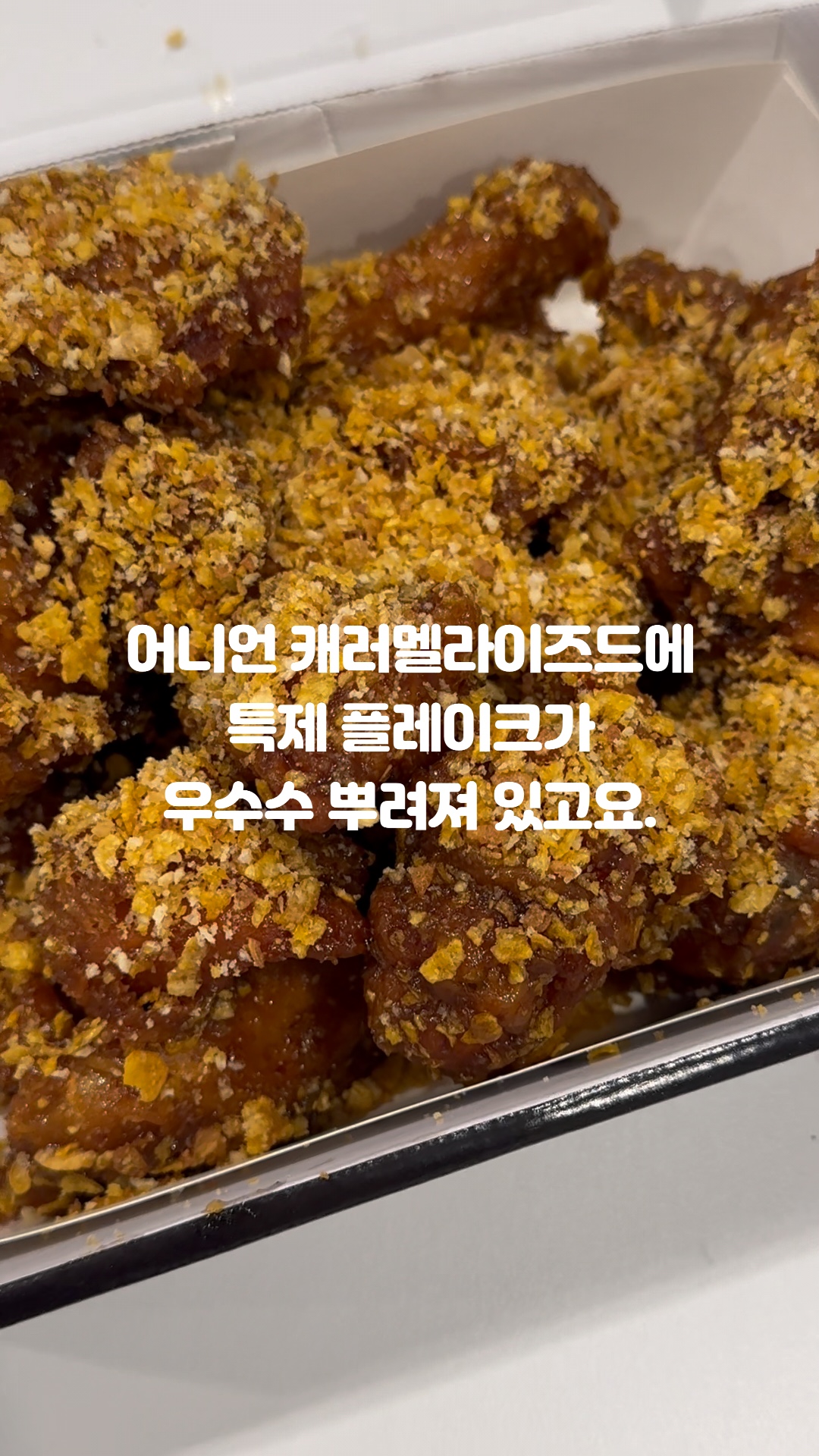 용기 안에 시리얼 조각을 뿌린 양념 튀김 음식이 담겨 있다