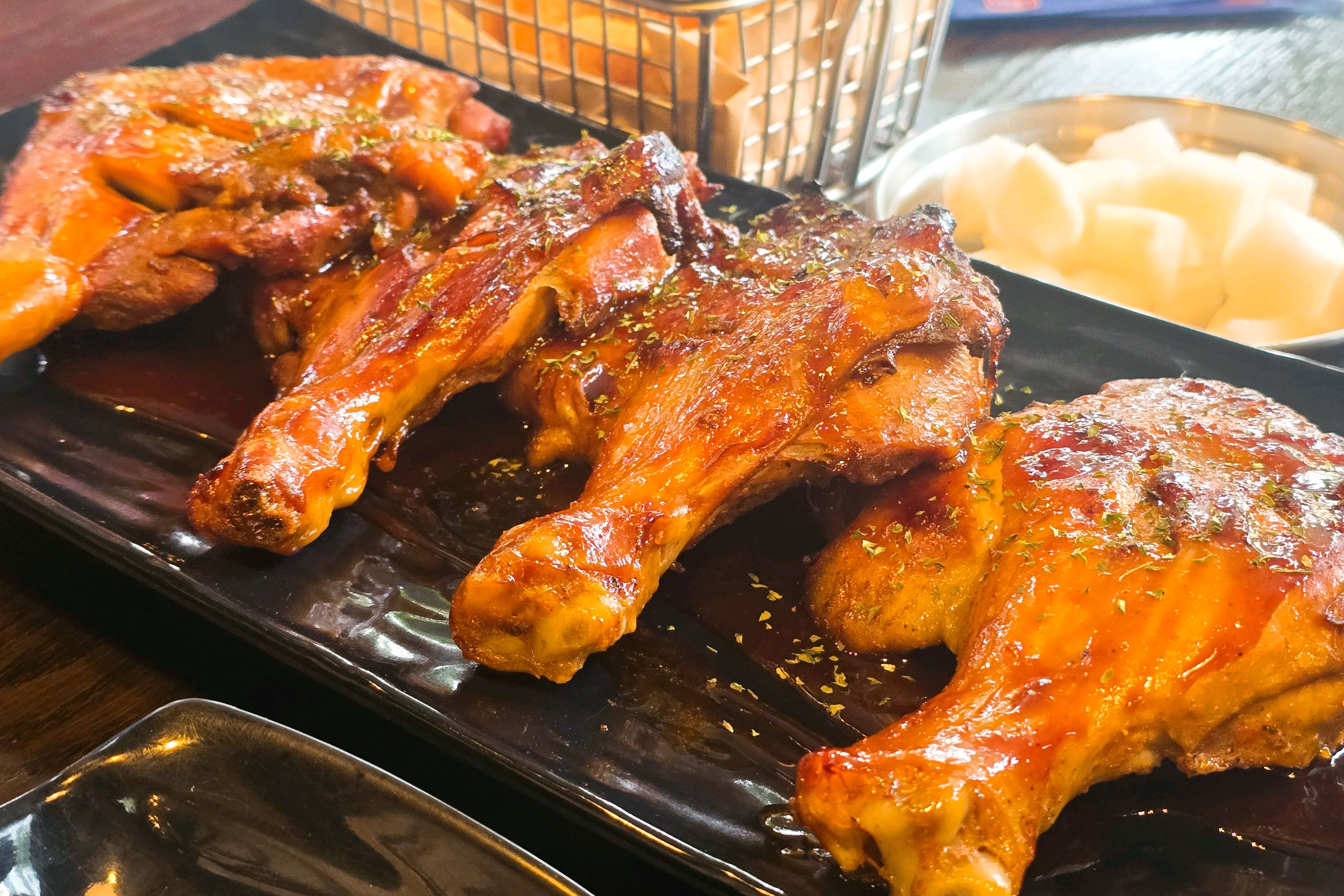 검은 접시에 소스를 바른 구운 닭고기 조각들이 담겨 있다