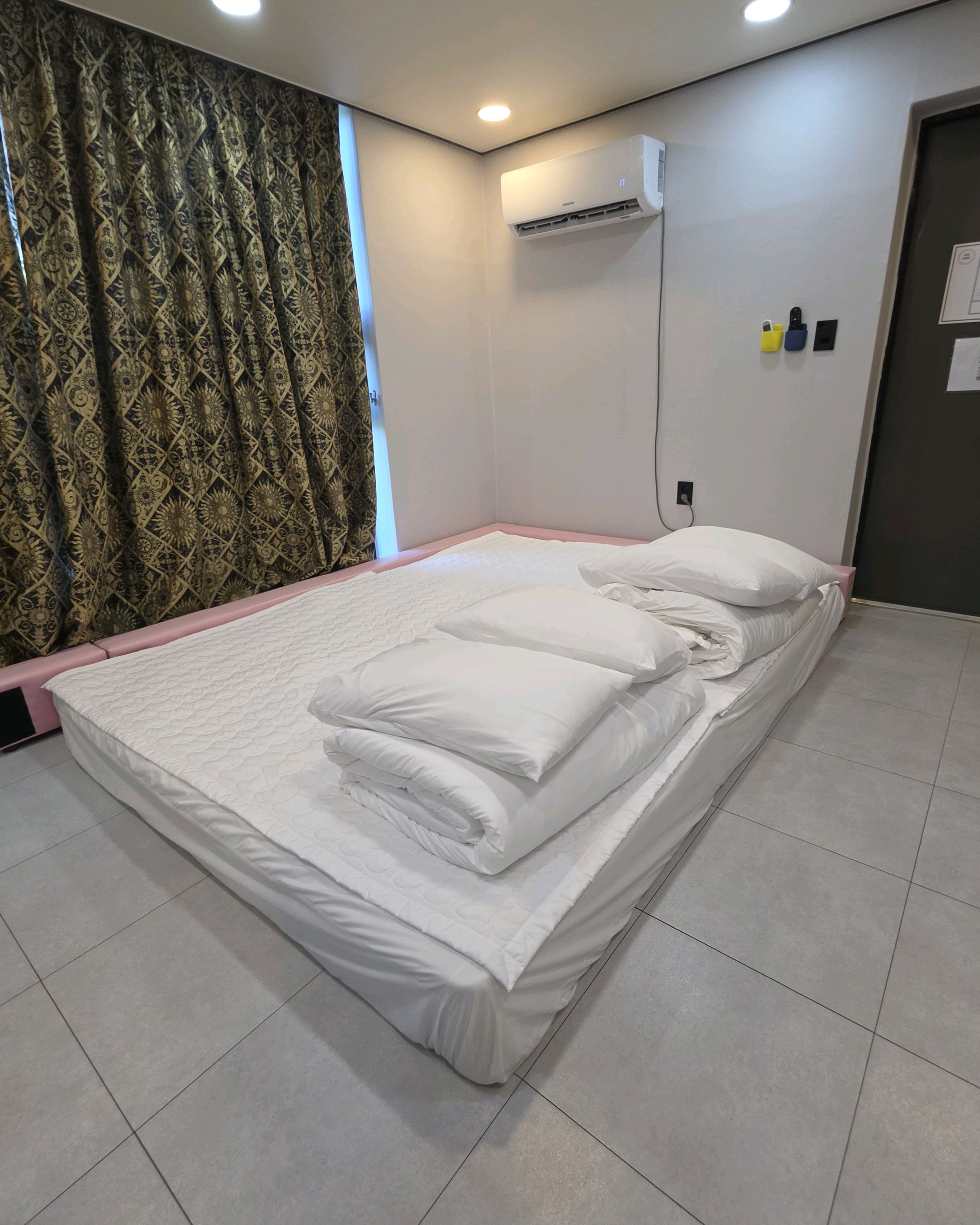 흰색 침구가 놓인 침대와 무늬 커튼이 있는 객실