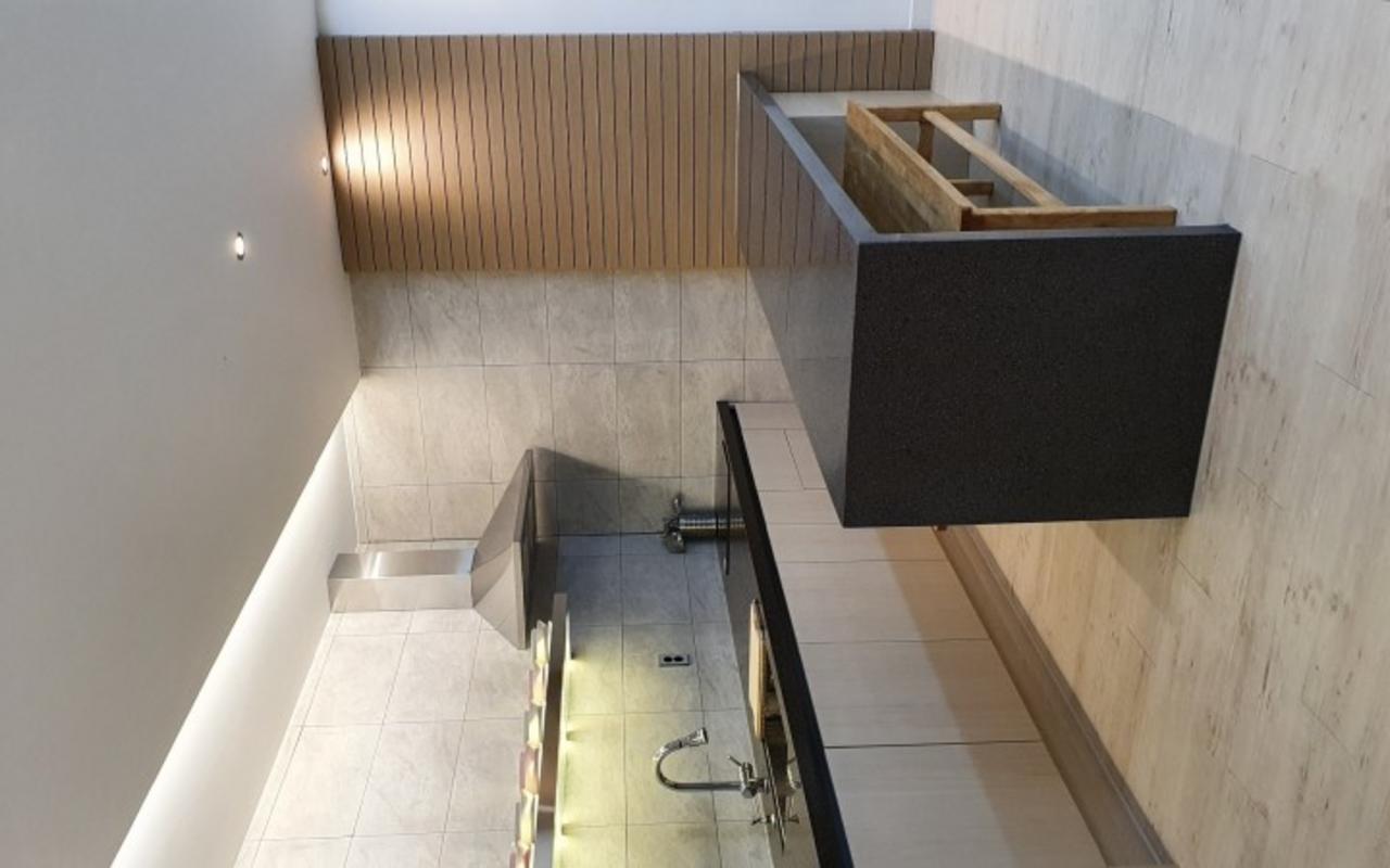 타일 벽과 세면대, 거울, 나무 가림막이 있는 욕실 공간이다