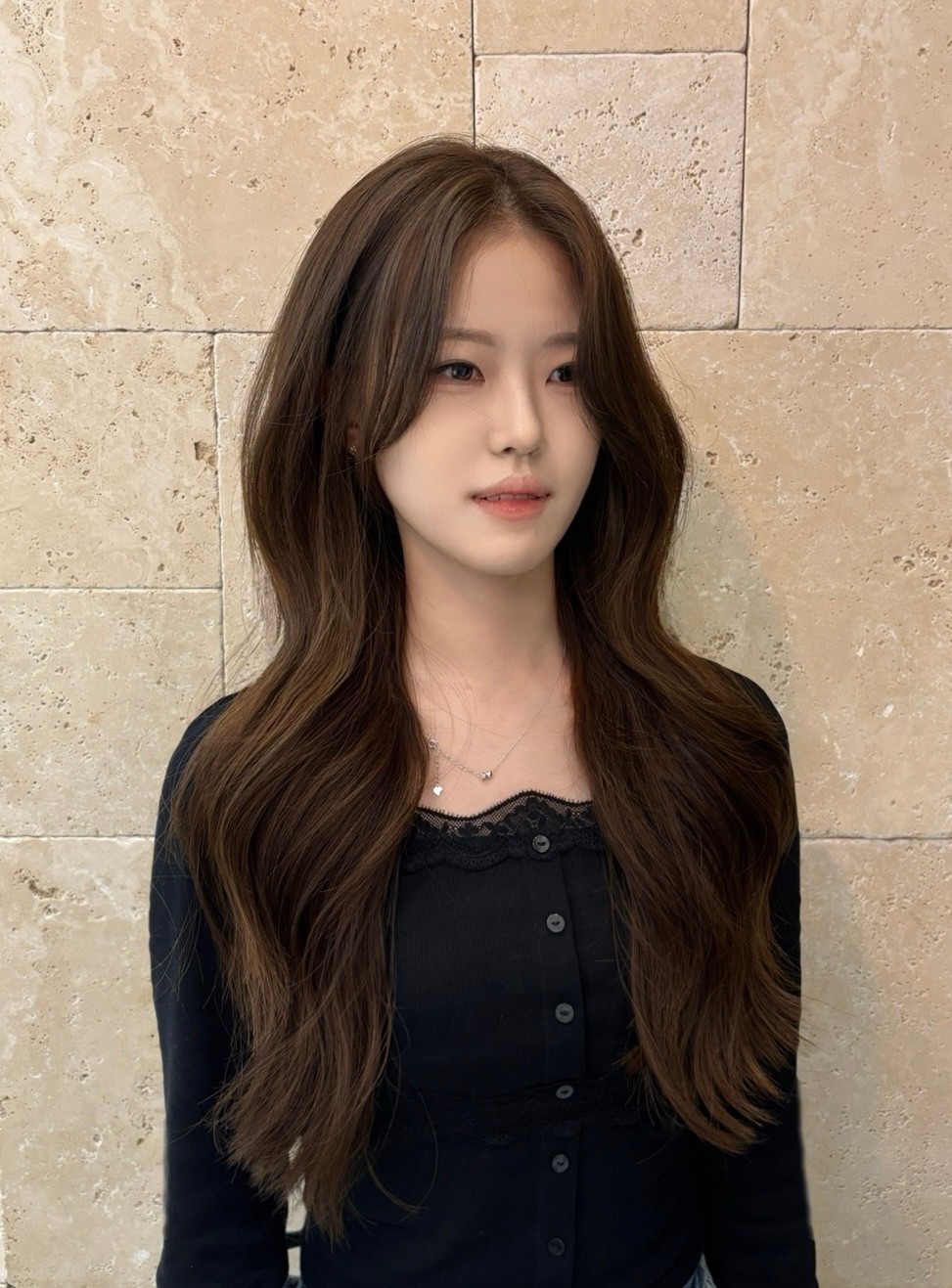긴 갈색 웨이브 머리의 여성이 정면을 보고 있는 모습