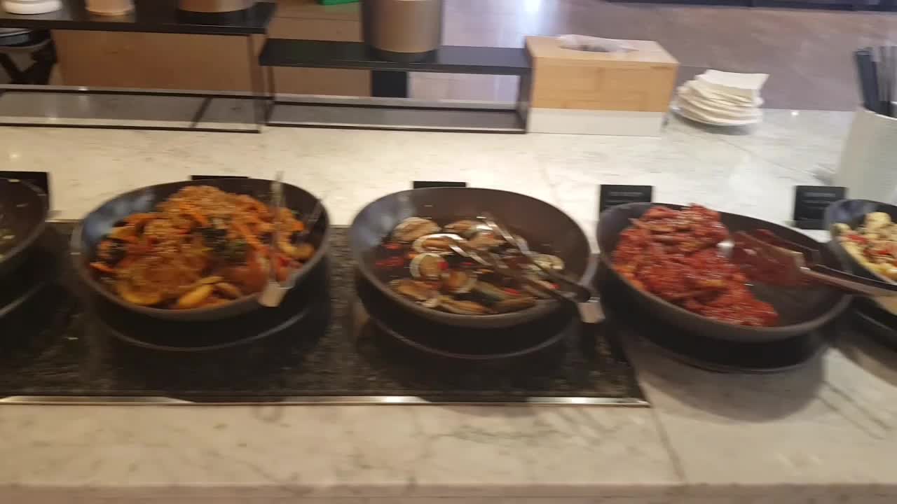 실내 뷔페 코너에 여러 음식이 검은 그릇과 접시에 담겨 있다