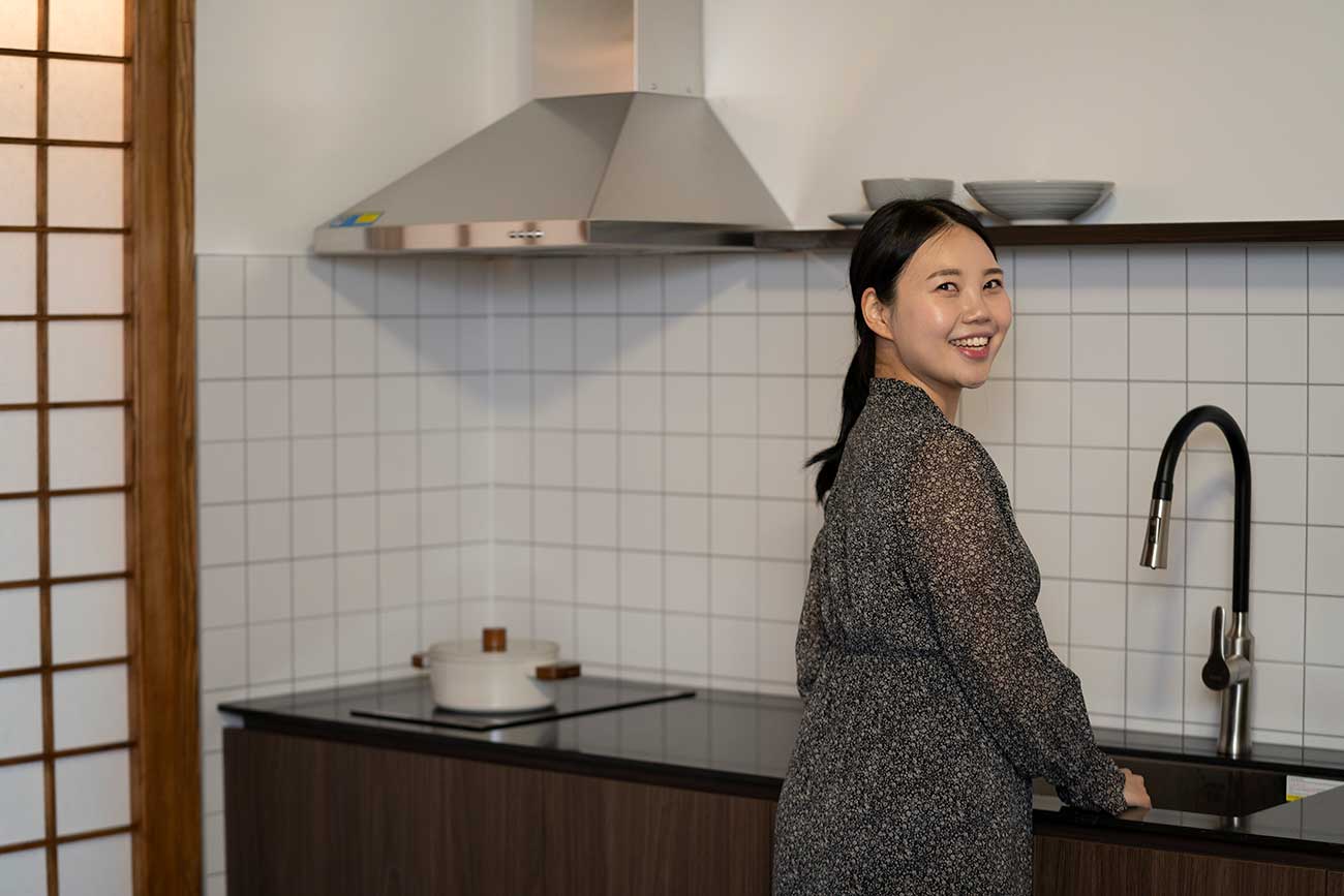 주방 싱크대 앞에서 포즈를 취하고 있는 여성의 모습
